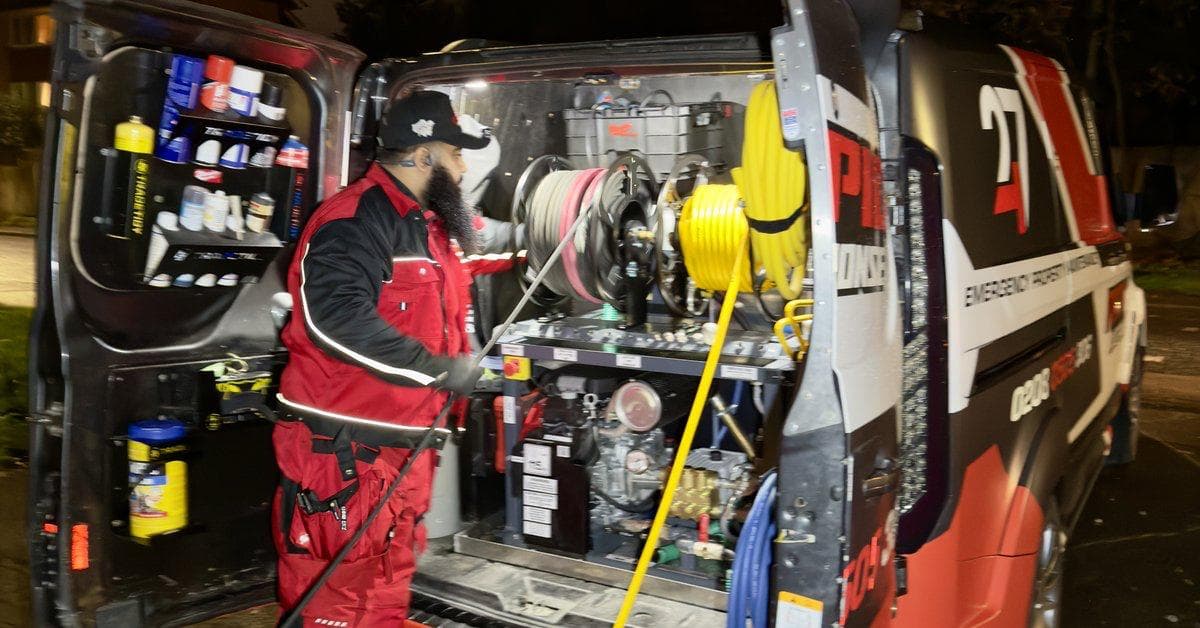 247 Rapid Response engineer at the rear of a fully-kitted emergency response van on a London street at night