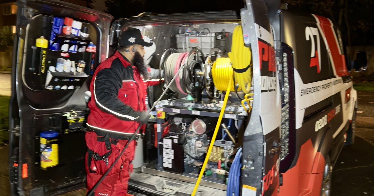 247 Rapid Response engineer at the rear of a fully-kitted emergency response van, high-pressure jetting kit ready, on a London street at night