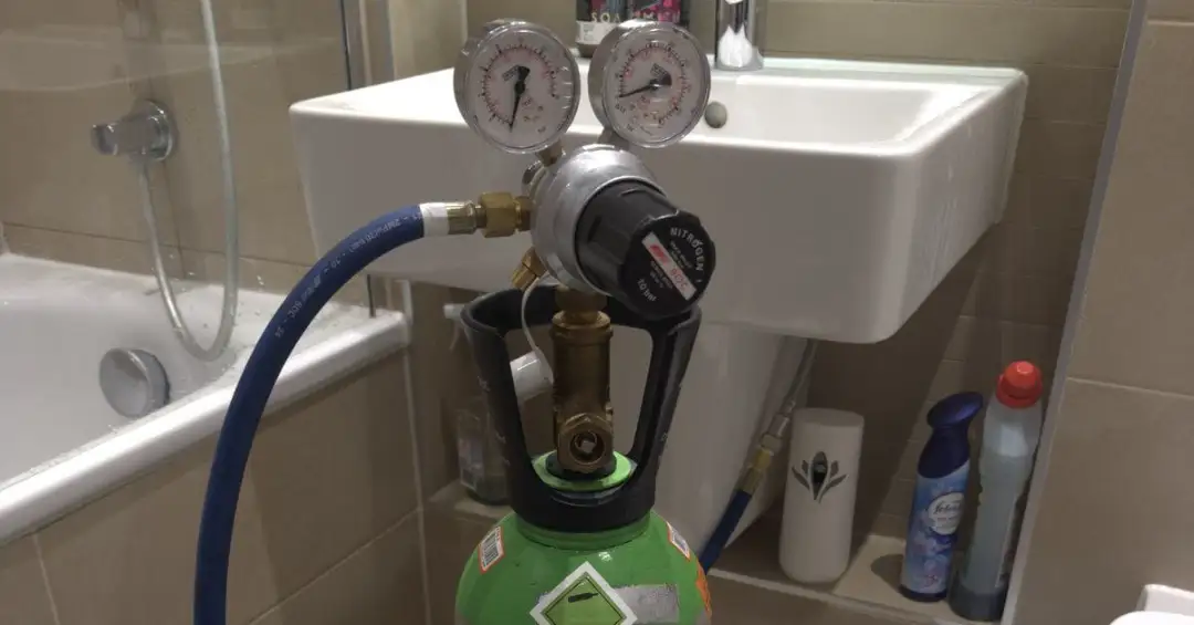 Nitrogen tracer-gas regulator and gauges set up next to a bathroom sink during a 247 Rapid Response leak-detection callout